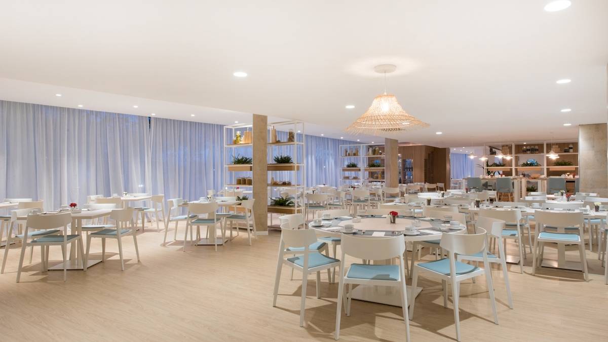 Innenraum des Restaurants im Iberostar Playa de Muro Hotel mit weißen Tischen und Stühlen.