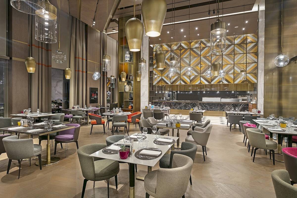 Innenansicht des Restaurants im Cullinan Belek Hotel mit gedeckten Tischen und modernen Leuchten.