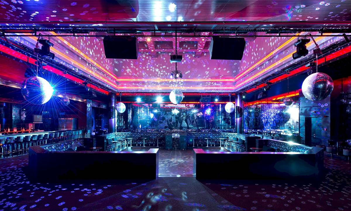 Disco-Saal im Gloria Serenity Resort mit lila und blauer Beleuchtung, Spiegelkugeln und Bar.