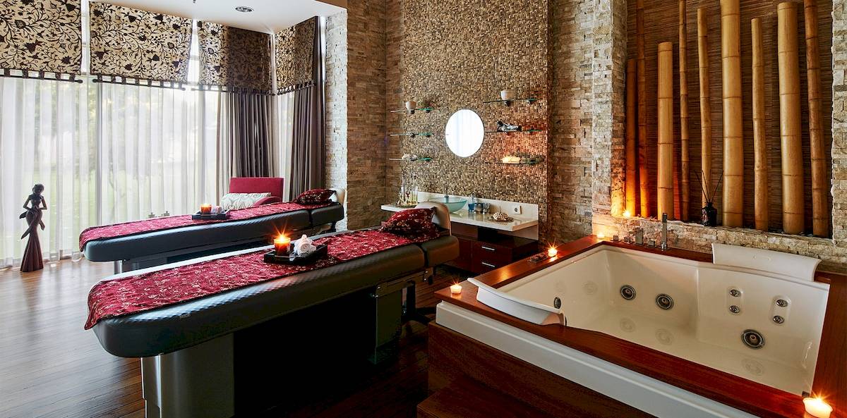 Spa-Behandlungsraum im Gloria Serenity Resort mit zwei Behandlungstischen und einer Badewanne.