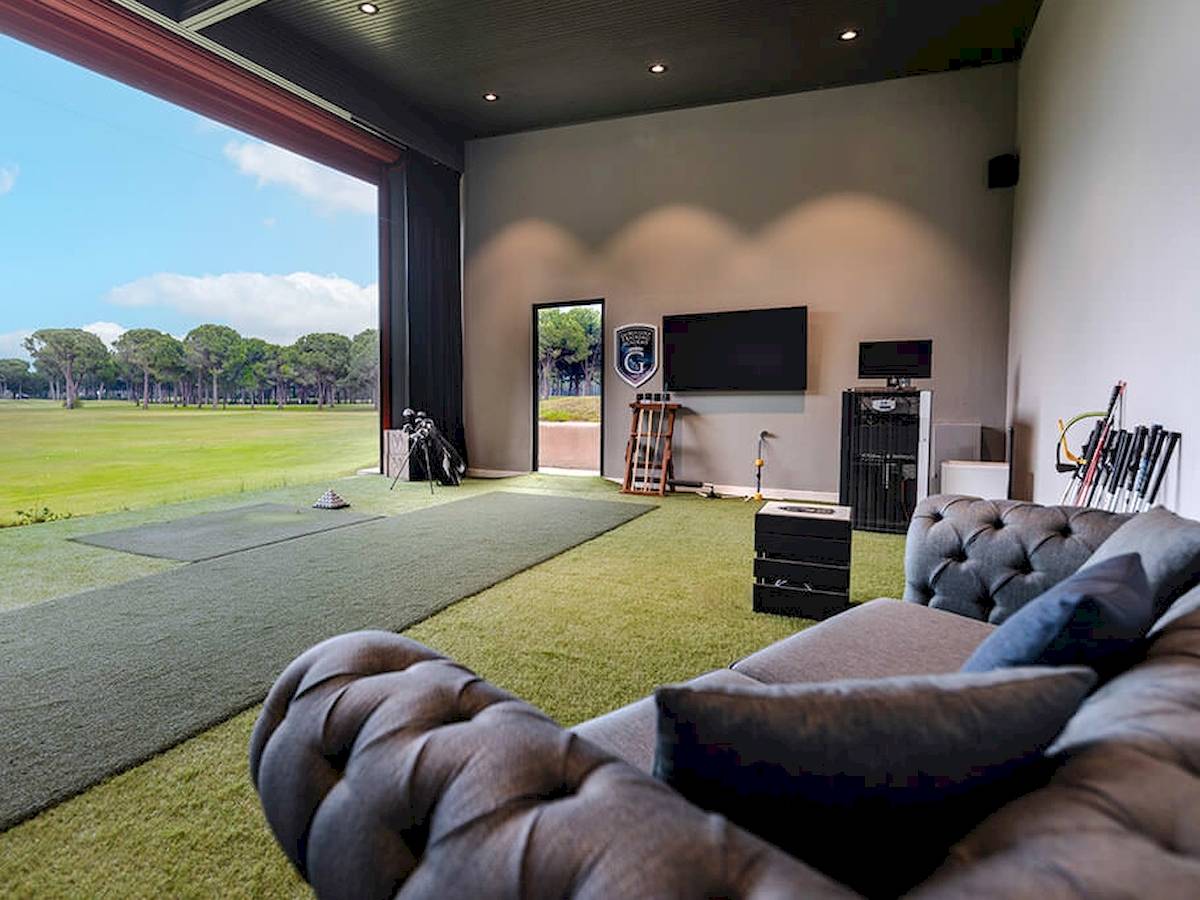 Innenansicht des Gloria Golf Resorts mit Wohnzimmer, Fernseher und Golfausrüstung.