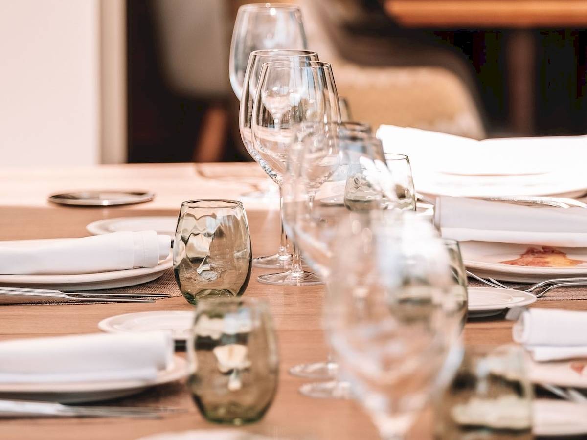Gedeckter Tisch im Aimia Hotel mit Gläsern, Tellern und Servietten.