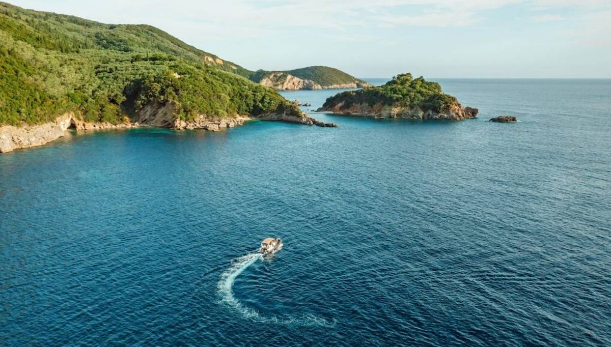 Ein Boot fährt auf dem Meer mit einer kleinen Insel im Hintergrund.