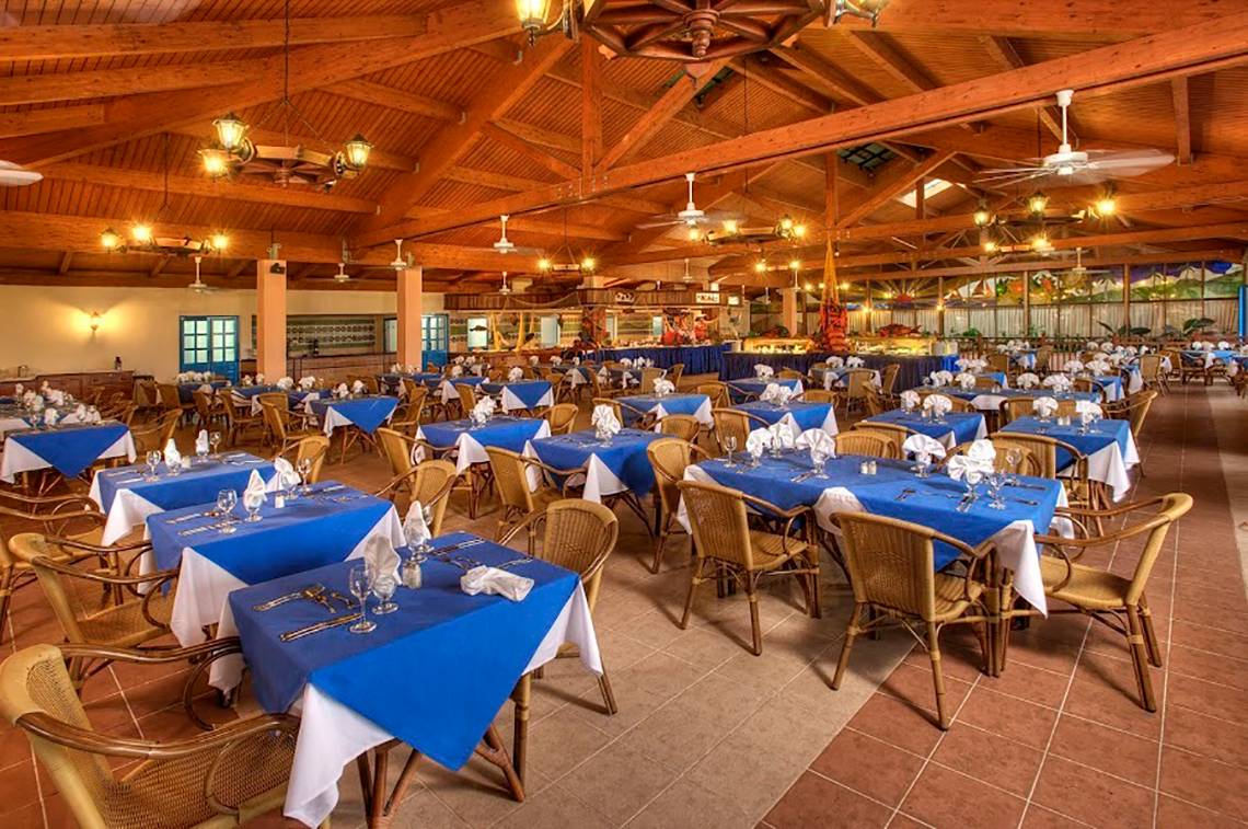 Innenansicht des Restaurants im Memories Jibacoa Resort mit blauen und weißen Tischdecken.