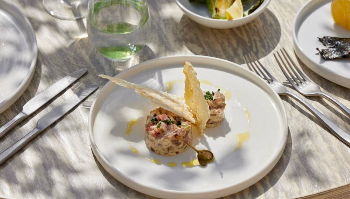 Ein weißer Teller mit zwei gebratenen Fleischgerichten und Beilagen, serviert im Ikos Olivia Hotel.