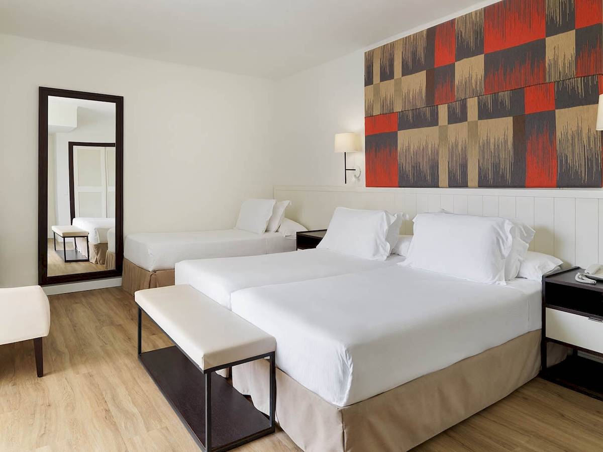 Doppelzimmer im H10 Casa del Mar Hotel mit zwei Betten, weißem Dekor und moderner Wandgestaltung.