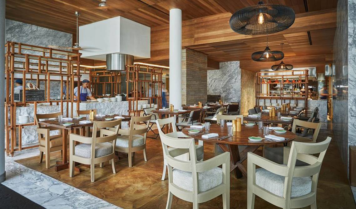 Innenansicht des Restaurants im FIVE Palm Jumeirah mit Holztischen, Stühlen und Holzelementen.