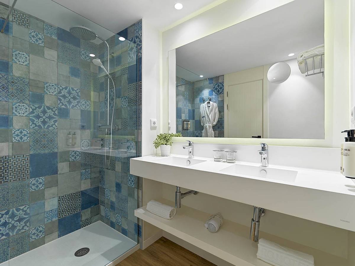 Badezimmer des H10 Casa del Mar mit blauen gemusterten Fliesen und einer großen Dusche.