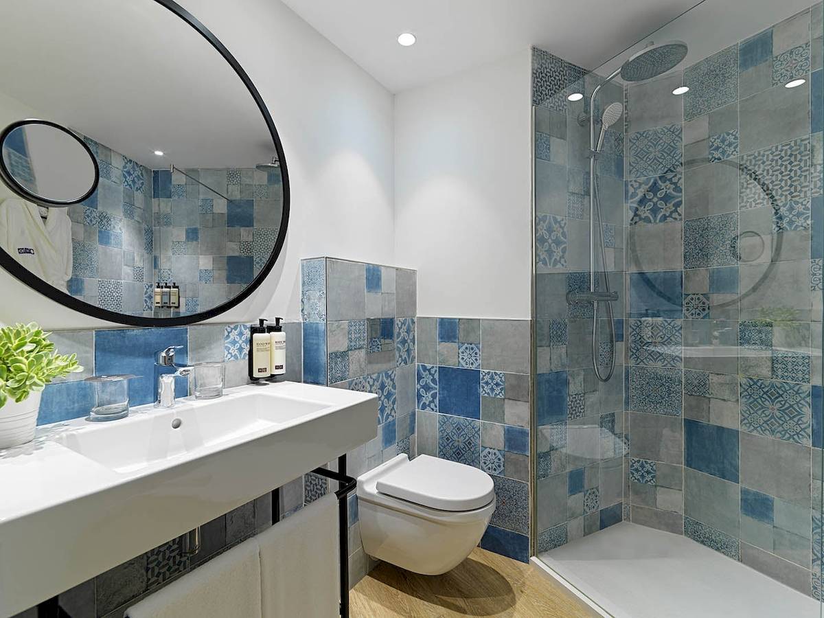 Badezimmer im H10 Casa del Mar Hotel mit blauen und grauen Fliesen, Dusche und Toilette.