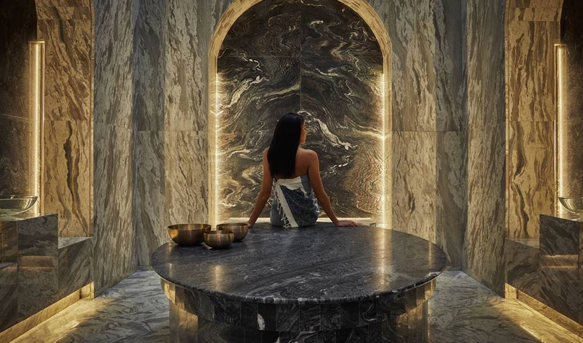 Eine Frau im Spa-Bereich des FIVE Palm Jumeirah mit Blick auf eine Marmorwand.