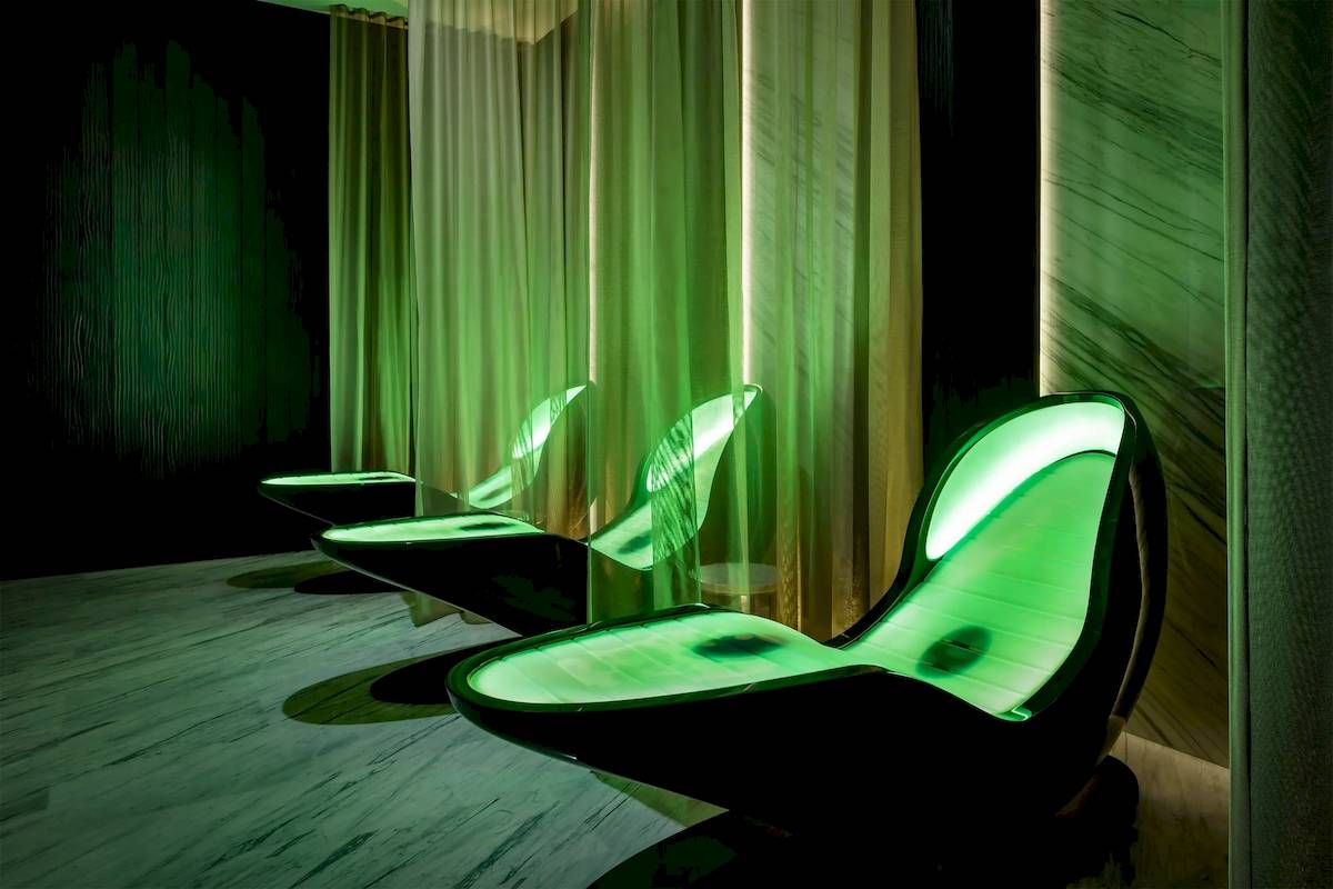 Lounge-Sauna im Atlantis The Royal Hotel mit grünen Leuchtsitzen und grünen Vorhängen.