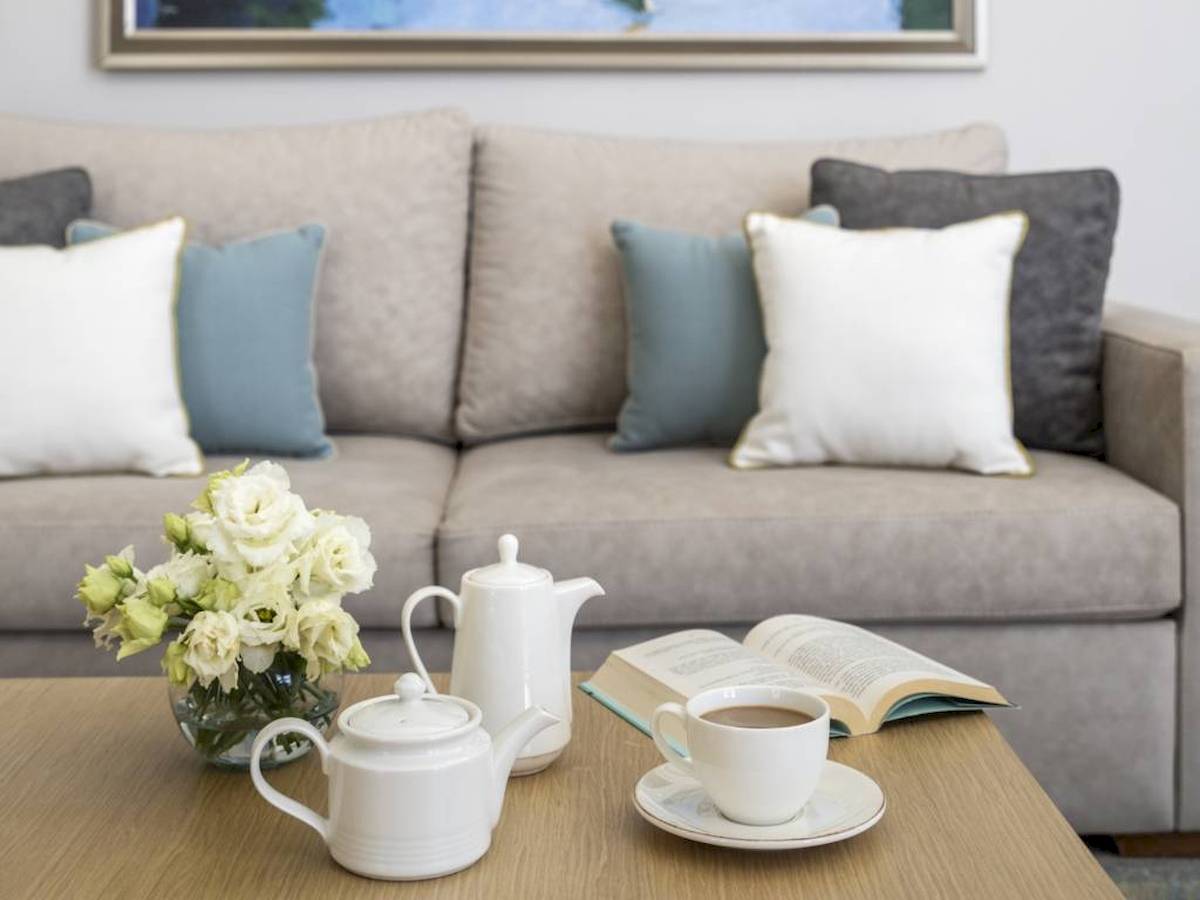 Hotel-Lounge mit Sofa, Tisch, Blumen, Teekannen und Kaffeetasse