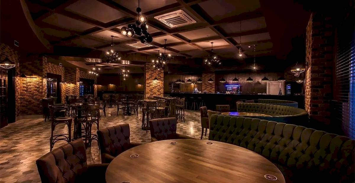 Innenbereich des Eftalia Ocean Hotels mit gepolsterten Stühlen und Tischen, Ziegelwänden und einer Bar.