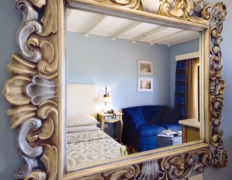 Spiegel im Hotelzimmer von CPH Pevero mit Blick auf ein Bett und ein Sofa