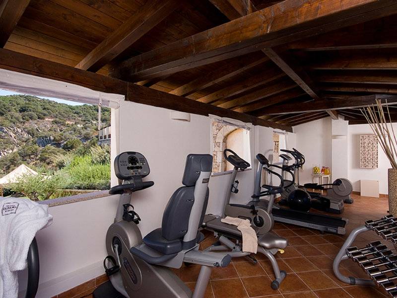 Fitnessstudio im CPH Pevero Hotel mit Blick auf die Berge und modernen Trainingsgeräten.