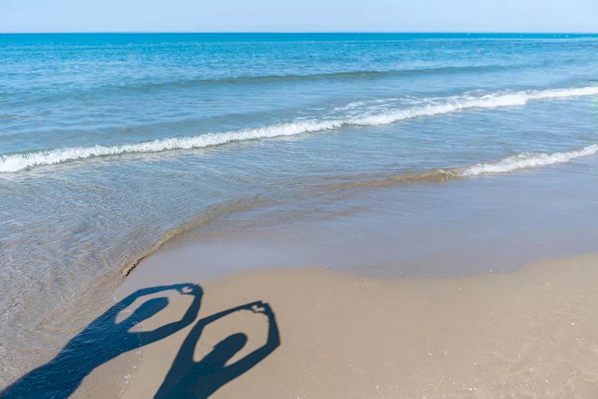 Schatten von zwei Personen, die ein Herz formen, auf dem Strand des Melas Resorts.
