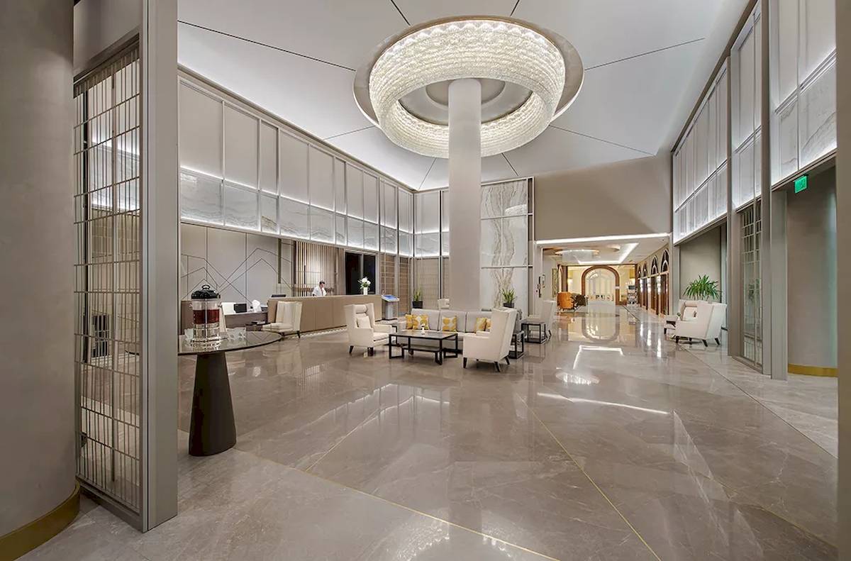Lobby des Melas Resorts mit moderner Einrichtung, großer Kronleuchter und helle Marmorböden.