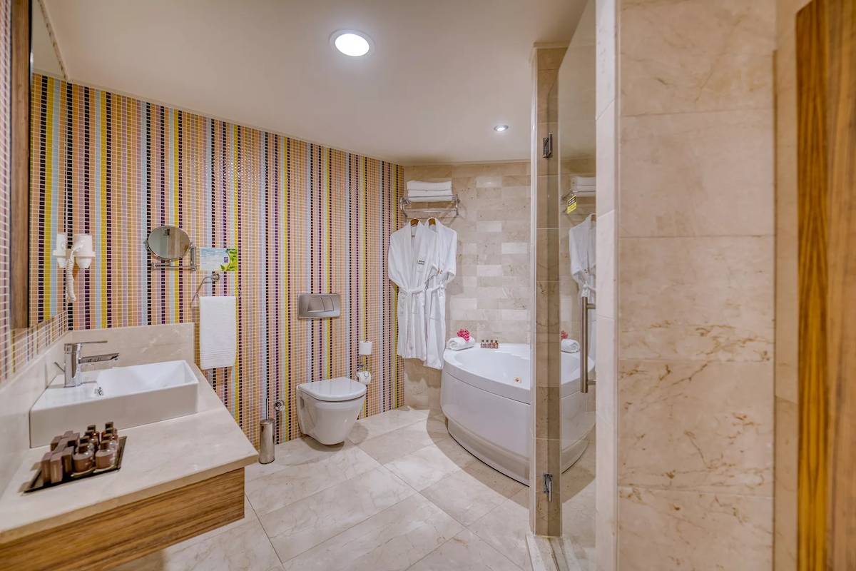 Badezimmer im Melas Resort mit Badewanne, Toilette und Waschbecken.