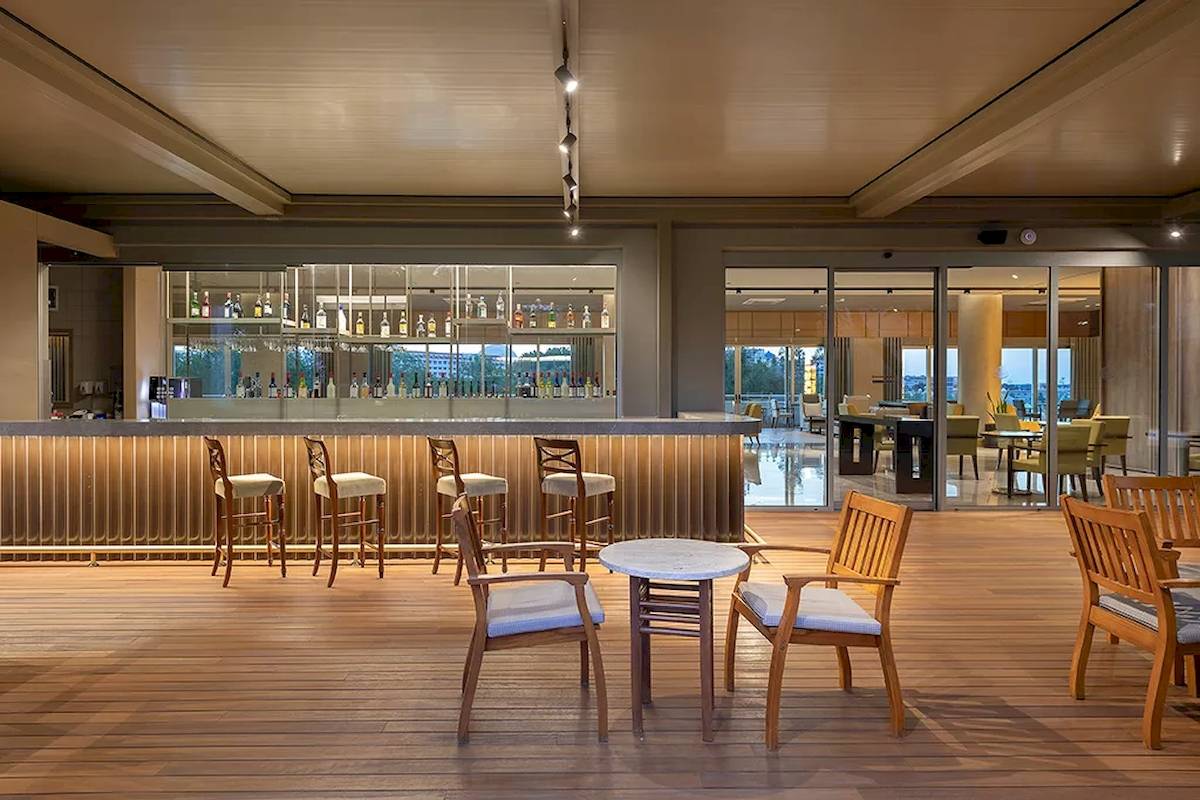 Innenansicht der Bar im Melas Resort mit hölzernem Boden und Sitzgelegenheiten.