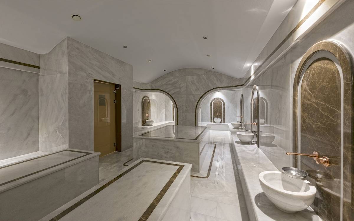 Innenansicht des Badezimmers im Novum Garden Side Hotel mit Marmorwänden und weißen Fliesen.