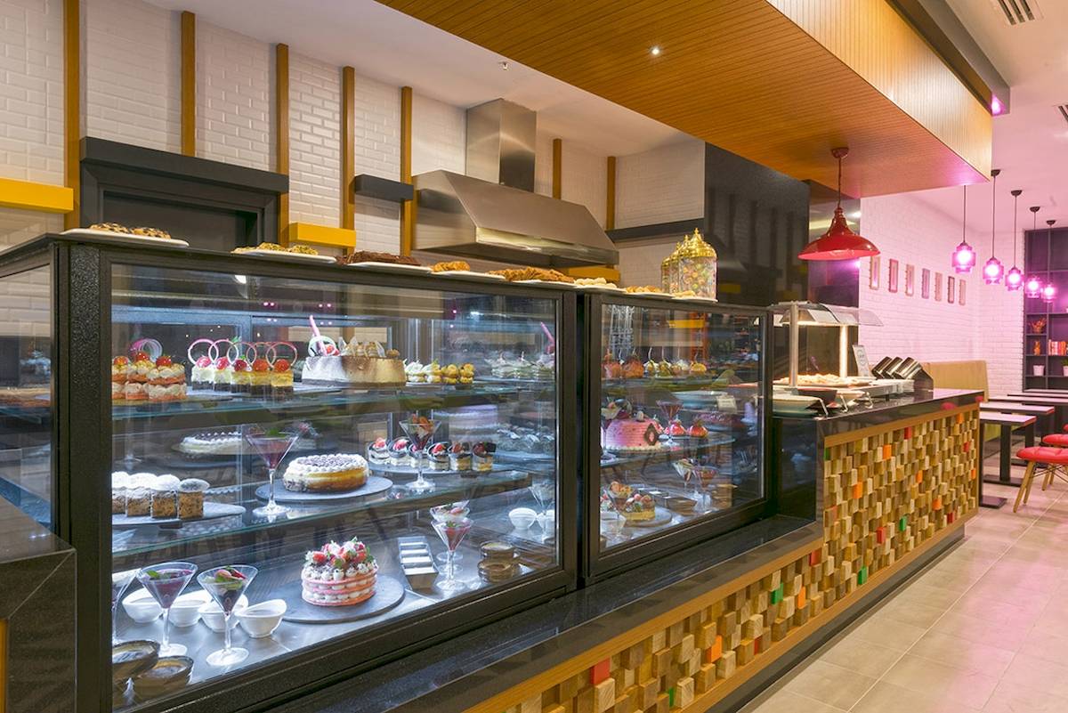 Innenansicht des Cafés im Novum Garden Side Hotel mit Vitrinen voller Kuchen und Desserts.