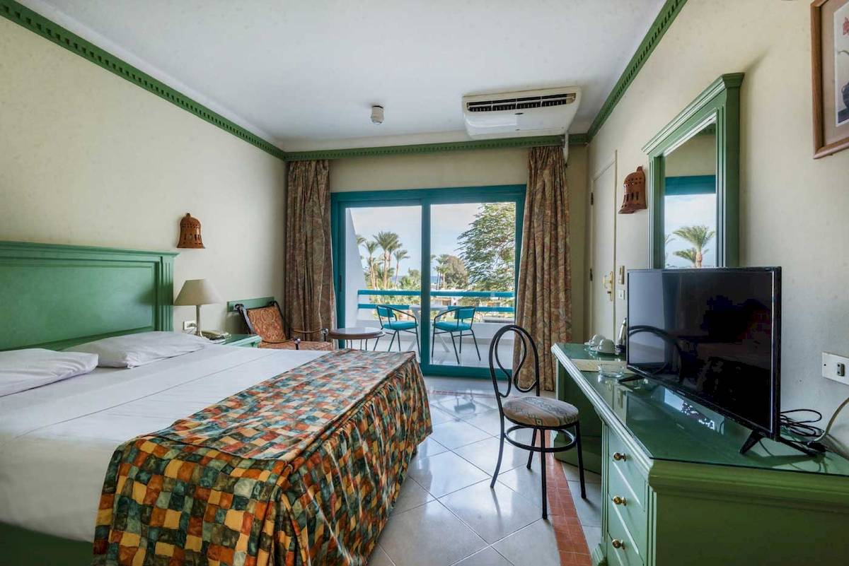 Zimmer im Shams Safaga Resort mit großem Bett, grünen Möbeln und Balkonzugang.