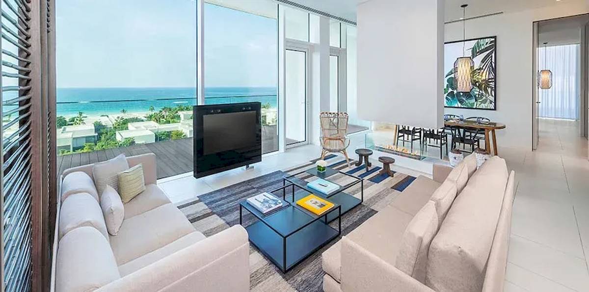 Wohnzimmer des Oberoi Beach Resorts in Al Zorah mit Meerblick, Flachbildfernseher, Sofas, Couchtisch und Esstisch.