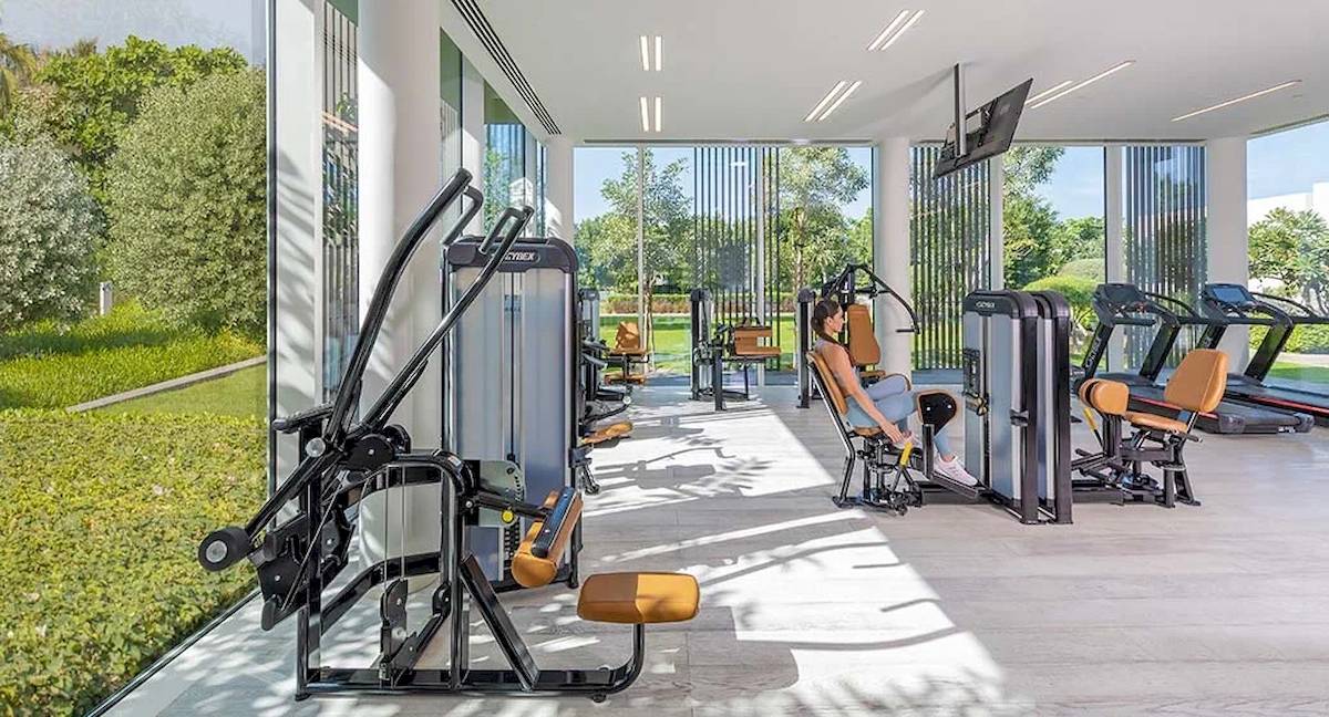 Fitness-Center im Oberoi Beach Resort Al Zorah mit modernen Geräten und einer Frau, die sich entspannt.