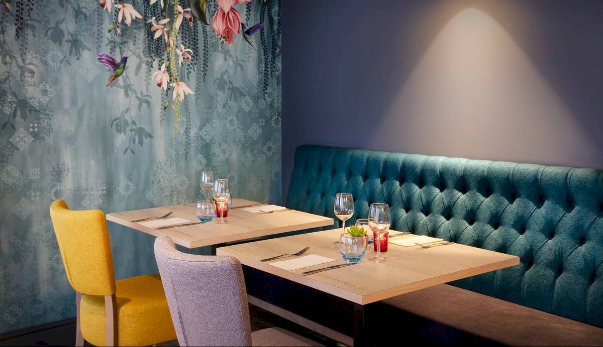 Innenbereich des Leonardo Hotel London Croydon mit zwei Tischen und einer Bank.