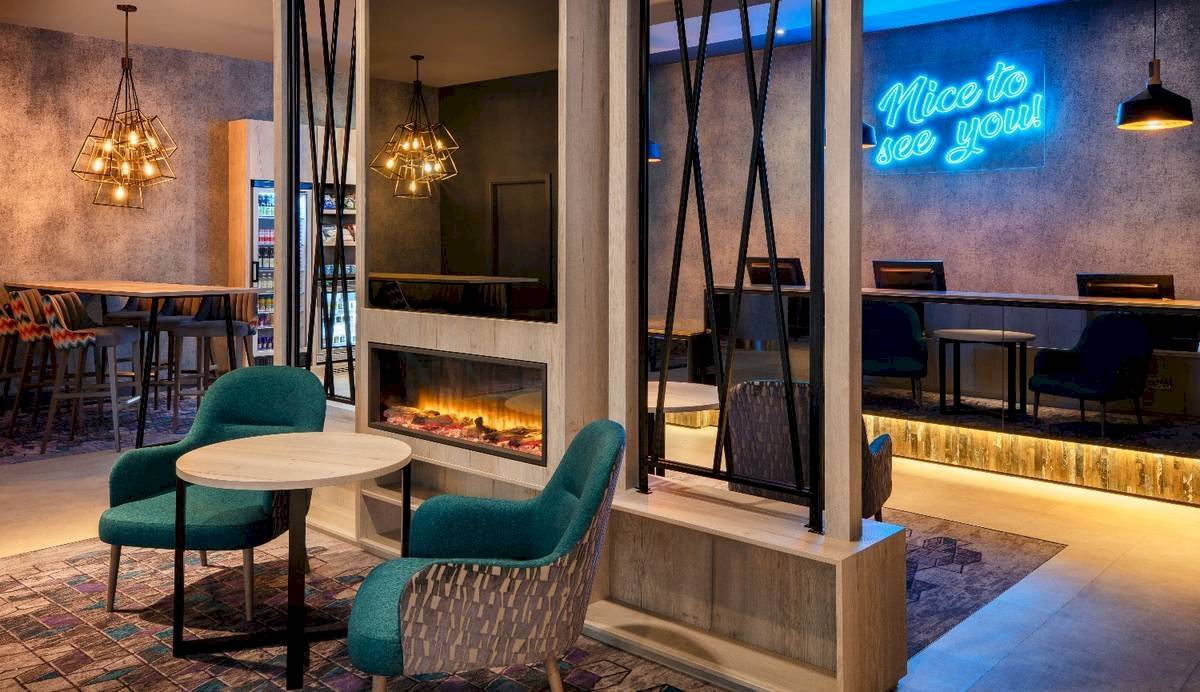 Leonardo Hotel London Croydon Lobby Lounge mit Kamin, grünen Stühlen und Schreibtischen.