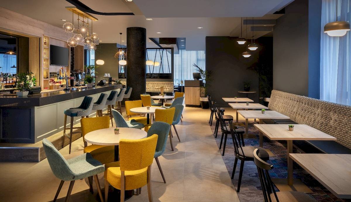 Innenbereich des Leonardo Hotel London Croydon mit Bar, Tischen und Stühlen.