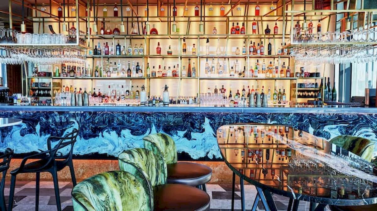 Bar im DoubleTree by Hilton Tower of London mit blauem Wanddesign und vielen Getränken