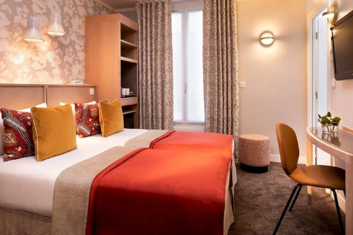 Doppelzimmer im Les Jardins d'Eiffel Hotel mit zwei Betten, farbigen Kissen und einem Schreibtisch.