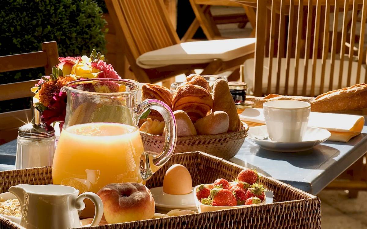Frühstücksbuffet im Hotel Les Jardins d'Eiffel mit Brot, Croissants, Früchten und Getränken.