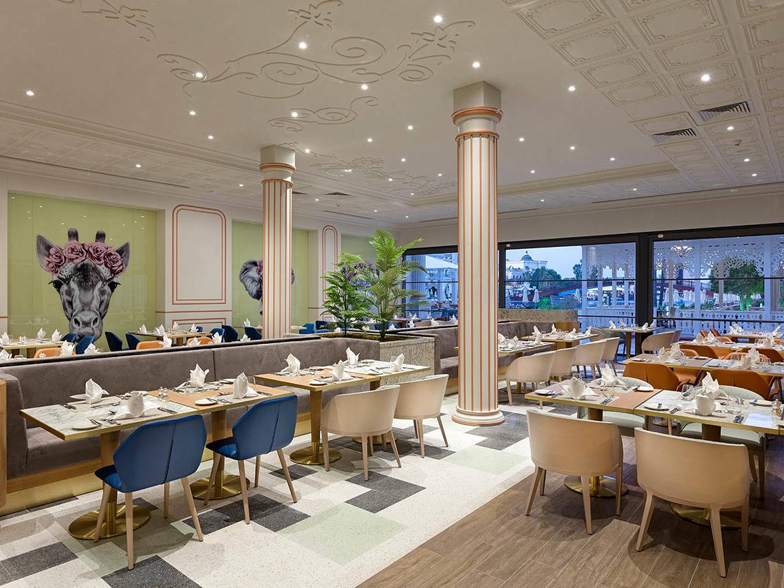 Innenansicht des Restaurants des Titanic Mardan Palace Hotels mit runden Tischen und Stühlen.