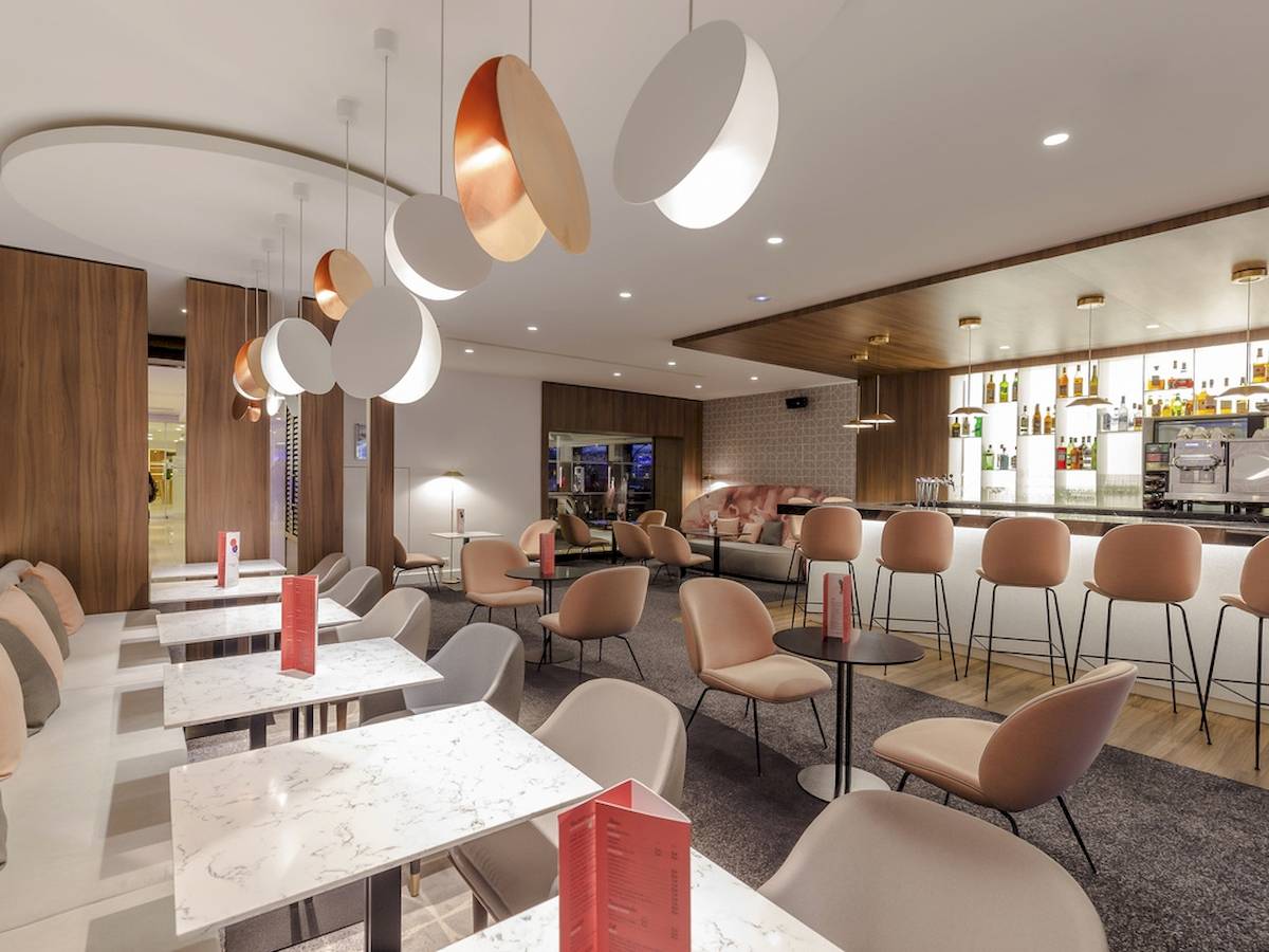 Innenbereich des Novotel Paris Tour Eiffel Restaurants mit modernen Möbeln, Marmortischen und Bar.