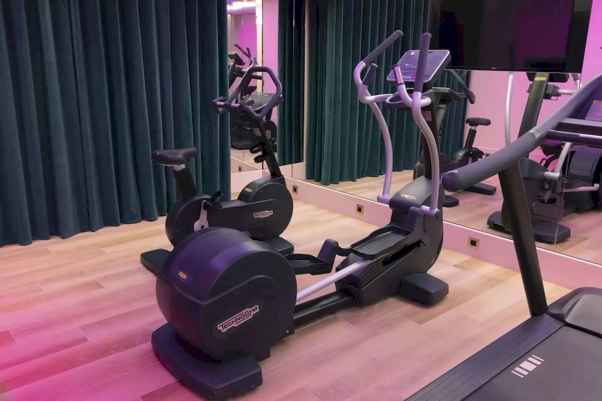 Fitnessbereich im Hotel mit einem Laufband und einer elliptischen Maschine neben einem Spiegel.