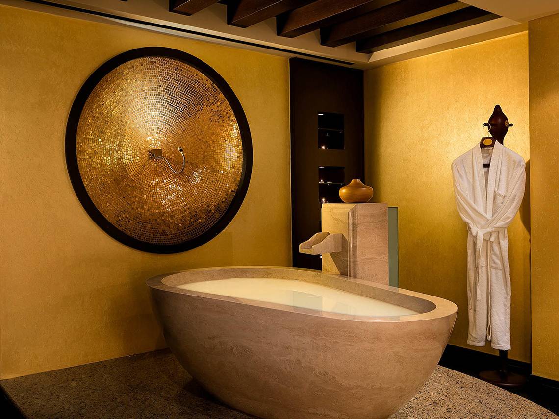Luxuriöses Badezimmer im Titanic Mardan Palace mit goldener Wand und freistehender Badewanne.