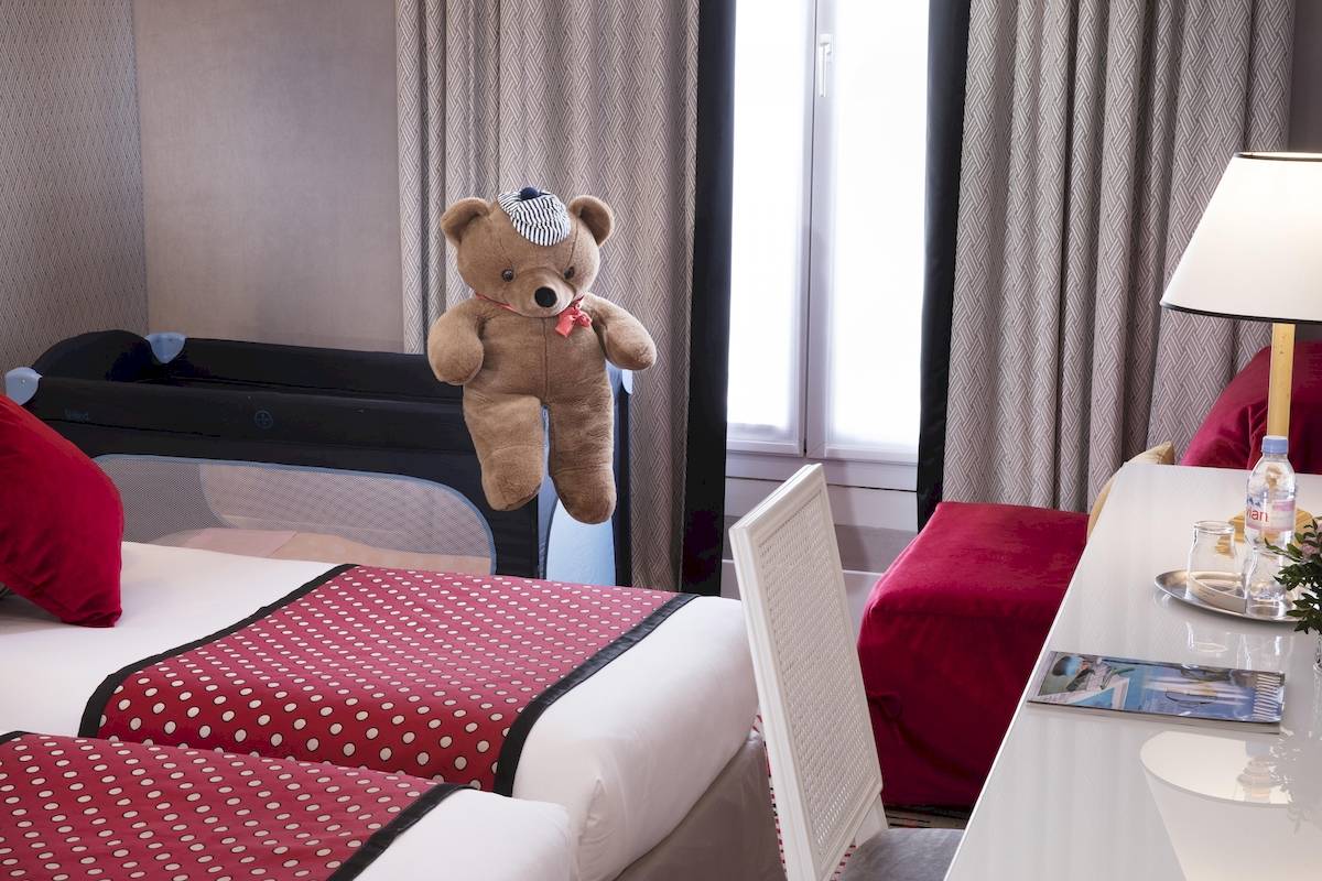 Zimmer im Victor Hugo Paris Kléber mit zwei Betten, rotem Teddybär und Babybett