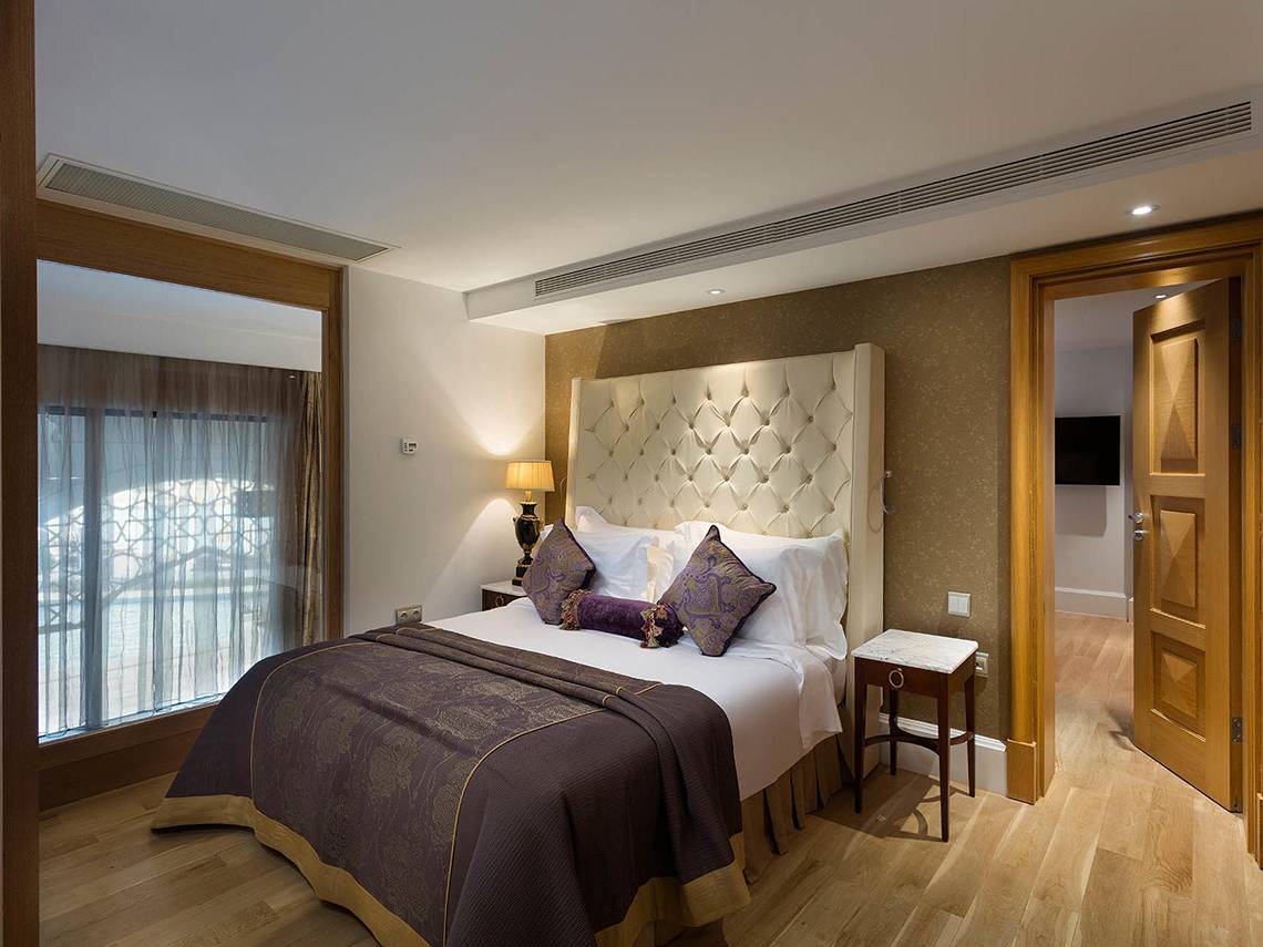 Ein elegantes Hotelzimmer im Titanic Mardan Palace mit einem großen Bett und bequemen Kissen.