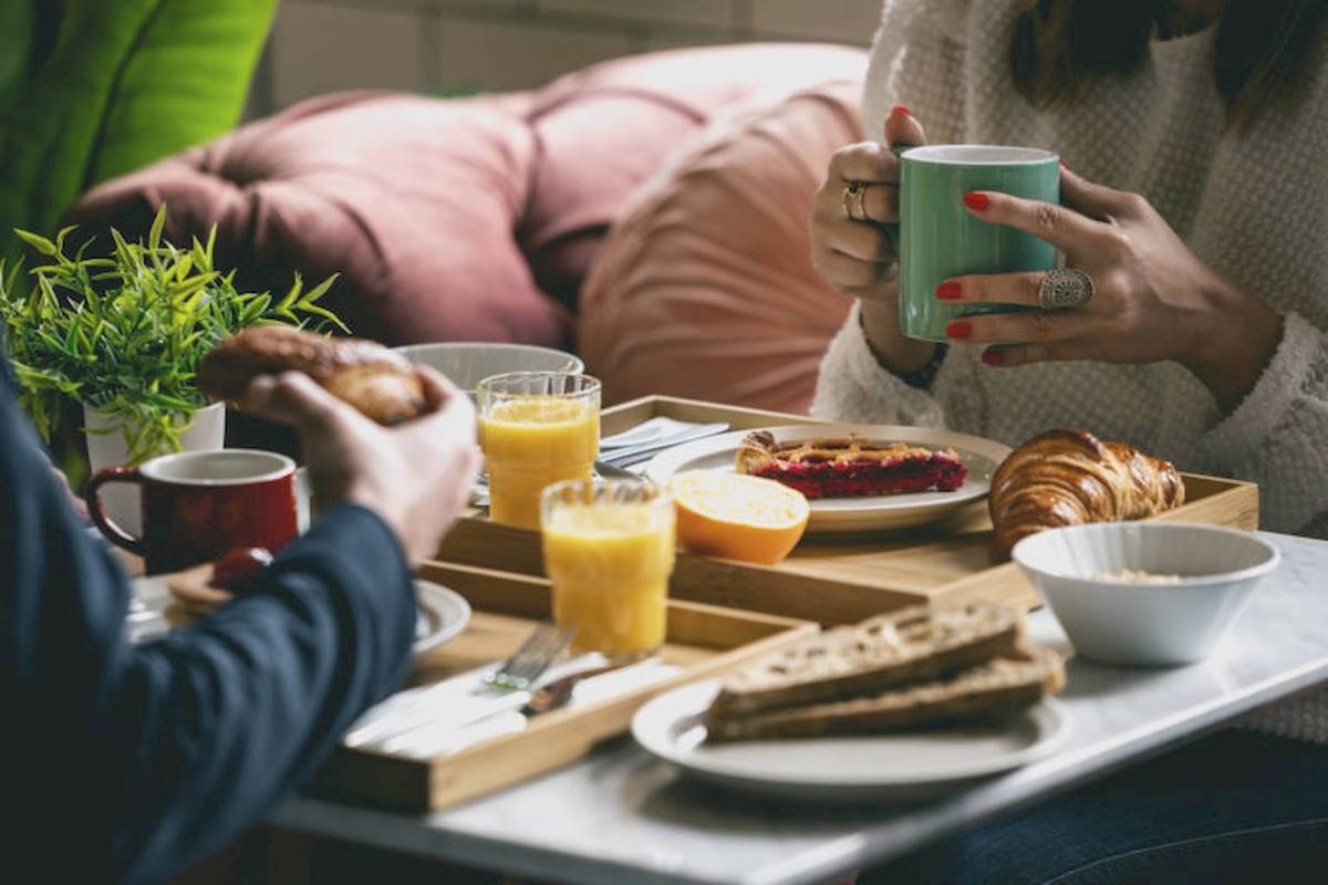 Zwei Personen frühstücken im ReMIX Hotel mit Kaffee, Orangensaft, Croissants und Brötchen.