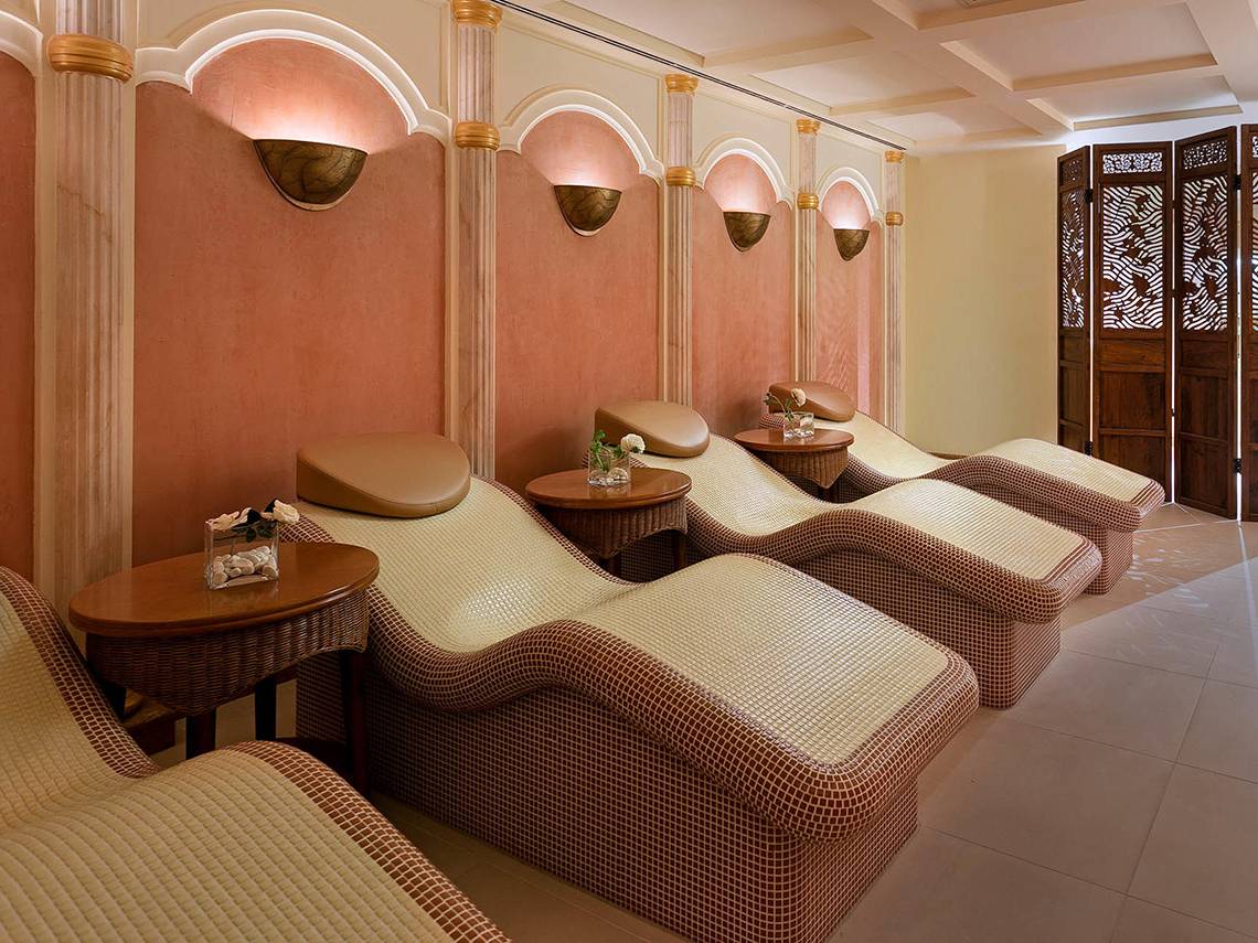 Massage-Lounge im Titanic Mardan Palace mit rosa Wänden und Liegen.