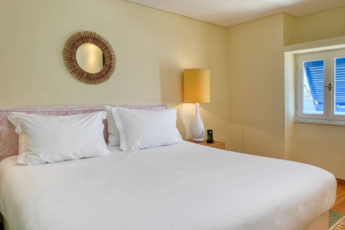 Schlafzimmer im Mykonos Theoxenia Boutique Hotel mit einem Bett, Lampen und Fenstern.