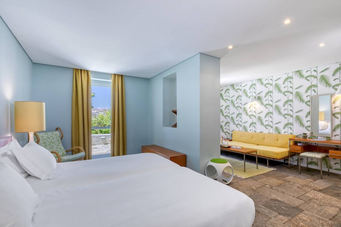 Innenansicht eines Zimmers im Mykonos Theoxenia Boutique Hotel mit weißen Möbeln und blauen Wänden.