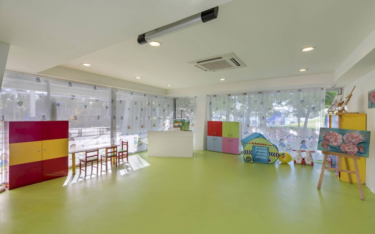 Kinderzimmer im Dobedan Exclusive Hotel & Spa Belek mit bunten Möbeln und grünem Boden.
