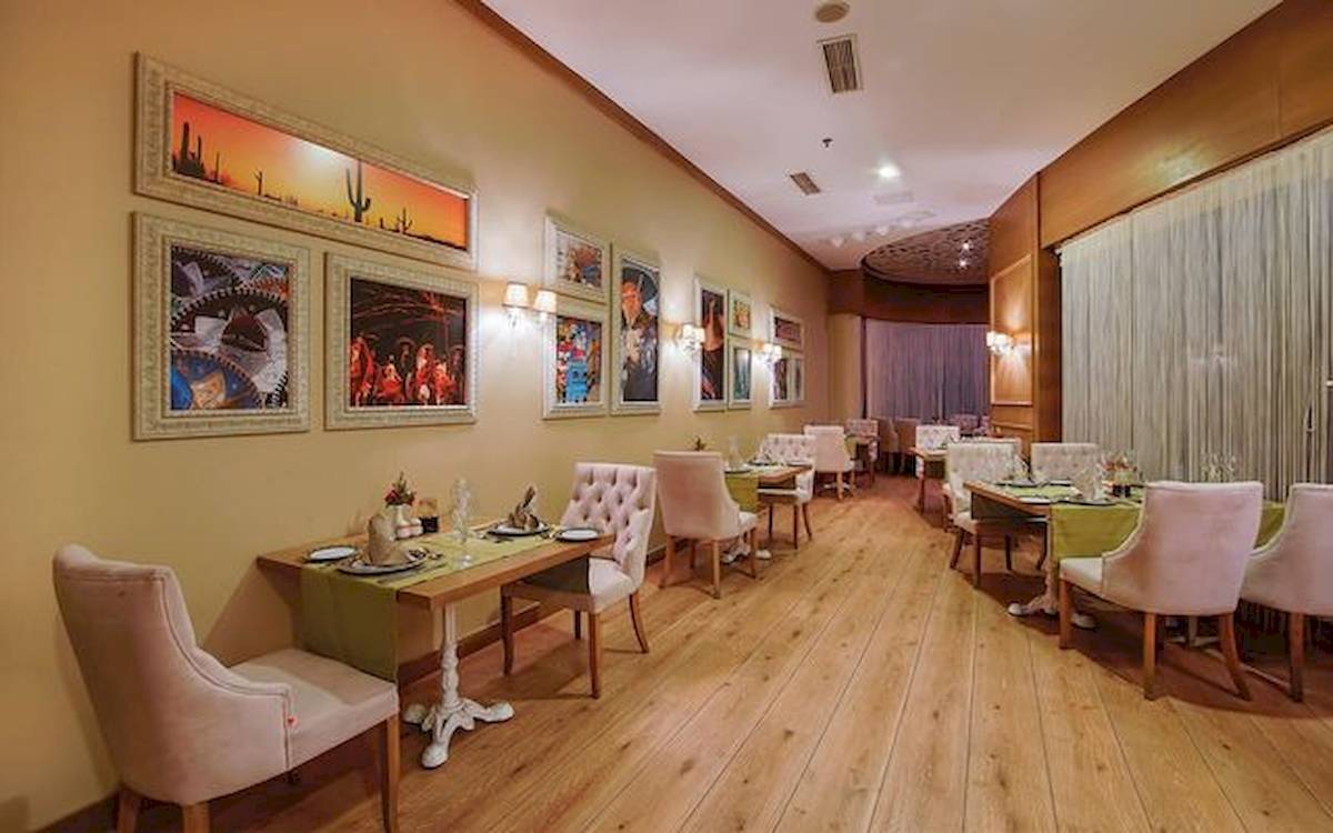 Innenraum des Restaurants im Limak Atlantis Deluxe Hotel & Resort mit farbenfrohen Wandgemälden und gepolsterten Stühlen.