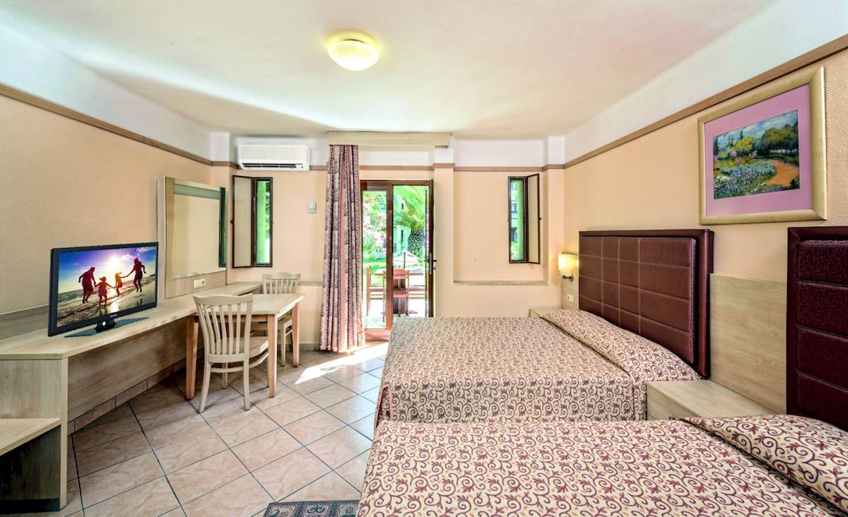 Innenansicht eines Zimmers im VONRESORT Golden Beach Hotel mit zwei Betten, Schreibtisch und Fernseher.