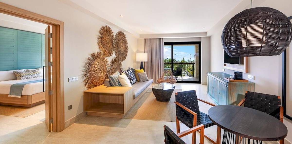 Innenansicht einer Hotelsuite mit Balkon, Wohnzimmer, Bett, Tisch und Stühlen.