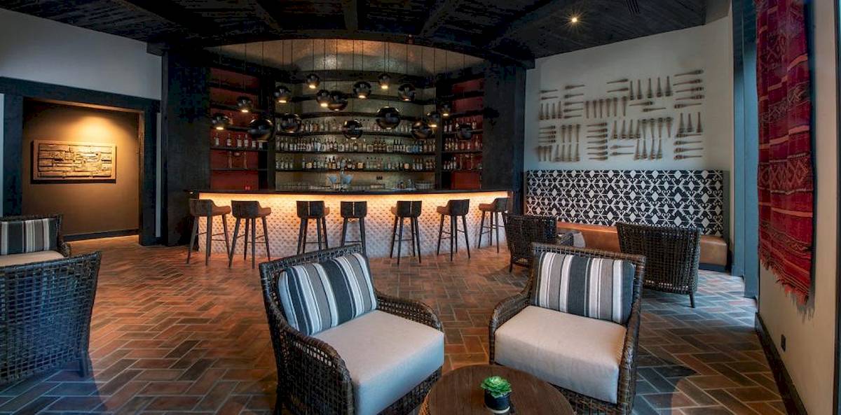 Innenansicht der Bar im Lopesan Costa Bavaro Resort Spa & Casino mit Thekenhockern und Wanddekorationen.