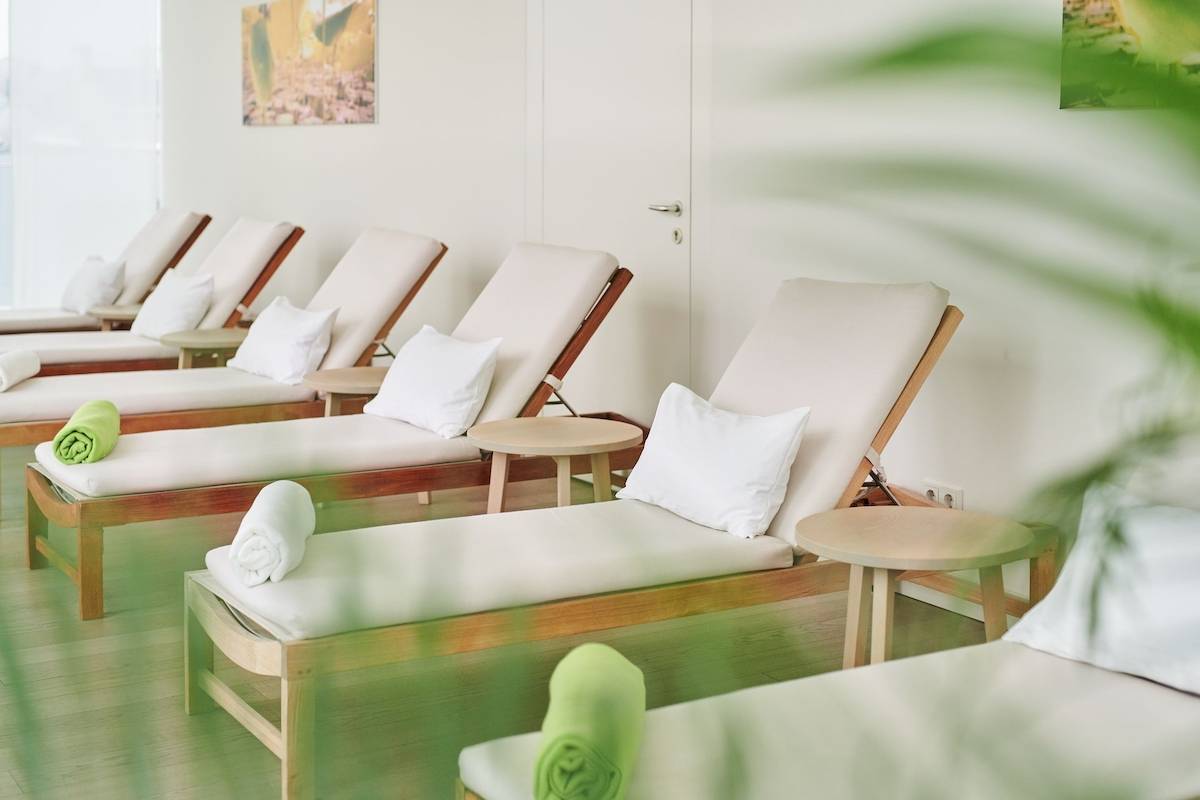 Loungebereich im MAXX by Steigenberger Vienna mit mehreren Liegen und grünen Handtüchern.